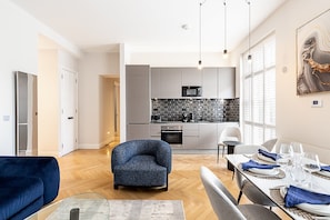 A modern kitchen with grey cabinets, a black backsplash, and stainless steel appliances. - Stylish Marylebone/Baker St Retreat (London)