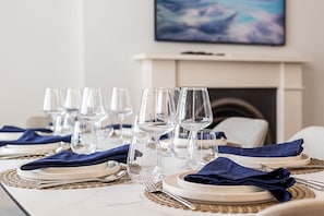 A dining table set with multiple wine glasses, plates, and cutlery, with a fireplace in the background. - Stylish Marylebone/Baker St Retreat (London)