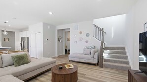 Una sala moderna con un sofá, una mesa de centro y una escalera que sube a un nivel superior.