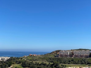 A coastal view with a building complex, greenery, and a clear sky. - Duquesa village El Hacho (Manilva)