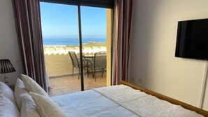 Una camera d'albergo con un letto, una televisione e vista sulla spiaggia.