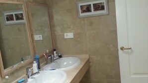 Un bagno con due lavandini, uno specchio, una porta e un piccolo quadro appeso al muro.