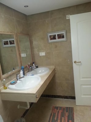 A bathroom with two sinks, a mirror, a door, and a small framed picture on the wall. - Duquesa village El Hacho (Manilva)