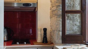 Una cocina con armarios de madera, un salpicadero de baldosas rojas, una pared de piedra y un ventanal.