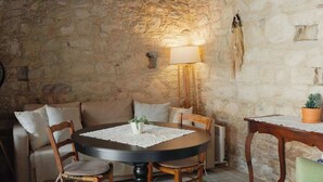 Una habitación acogedora con pared de piedra, una mesa redonda con sillas, un sofá, una lámpara y una pequeña mesa con una planta.