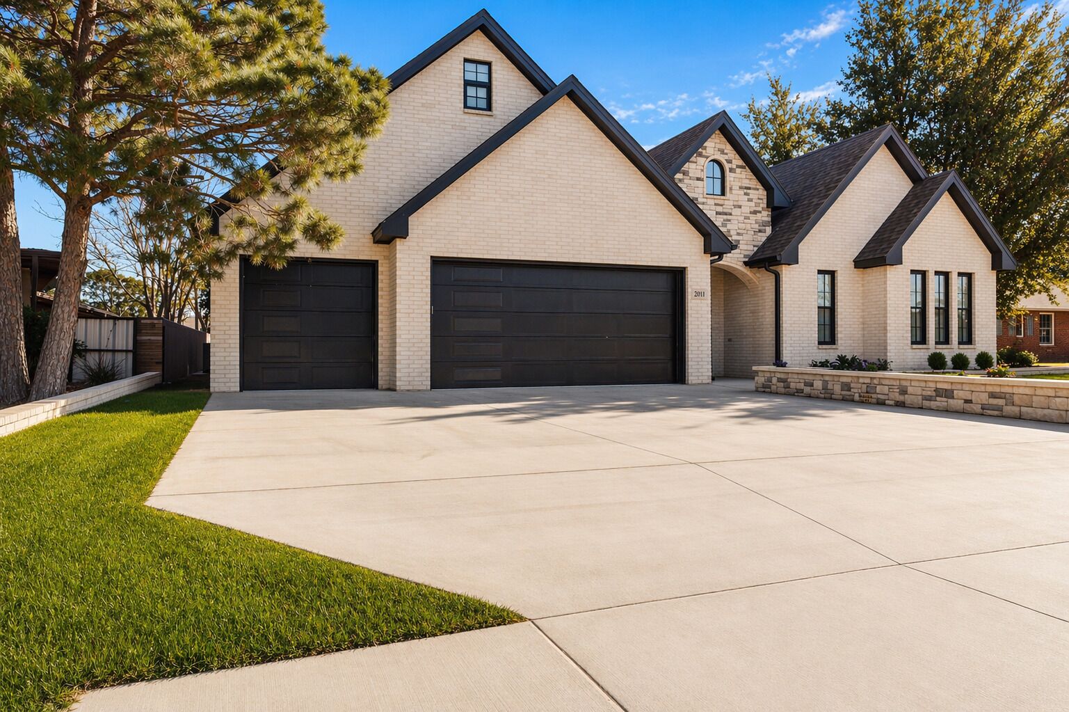A modern two-story house with a garage, a well-maintained lawn, and a clear sky.