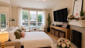 A bedroom with a bed, sofa, TV, fireplace, and a view of the outdoors. - Pool, Hot Tub, Huge Outdoor Theater, Mini Golf, Bowling, BBQ, Fire Pit,Sleeps 19 (Pflugerville)