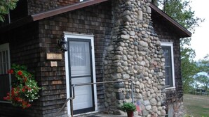 Ein Blockhaus mit Natursteinfassade, einer Holztür und einer kleinen Veranda mit Stufen.
