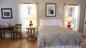 Ein Hotelzimmer mit einem großen Bett, zwei Nachttischen mit Lampen, einem Sessel, einem kleinen Tisch und einem gerahmten Bild an der Wand.