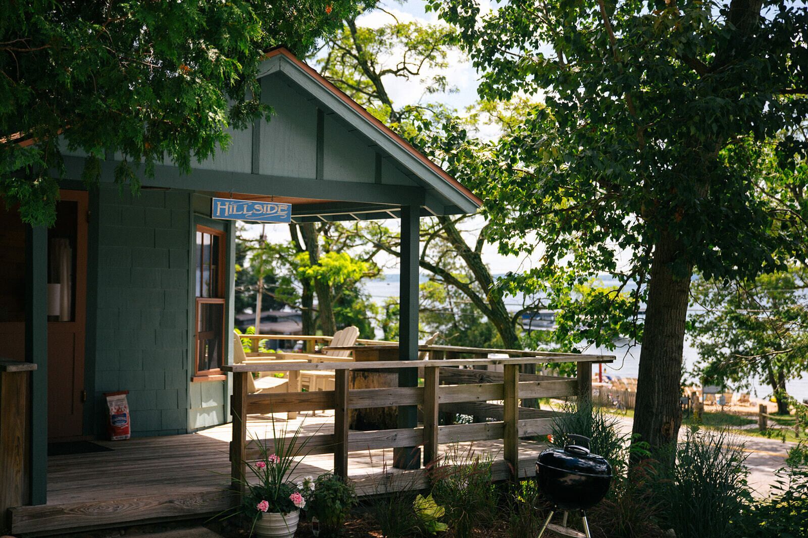 En hyggelig hytte med en overdækket veranda, grill og et skilt med teksten 'Hillside'.