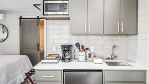 Una cocina moderna con microondas, cafetera y utensilios sobre la encimera.