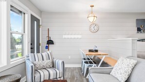 Una sala de estar moderna con sofá, sillas, una mesa de comedor, un reloj y una lámpara colgante.