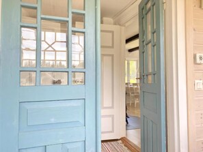 A hallway with a light blue door, a white door, and a view into a room with a dining table and chairs. - Your cottage, more Swedish than Sweden (Ryd)