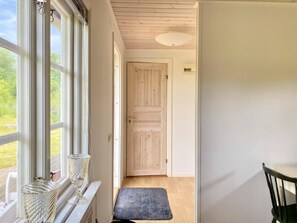 A hallway with a wooden door, a bench, and a window with a view of greenery. - Your cottage, more Swedish than Sweden (Ryd)