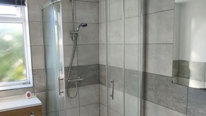 Un baño moderno con ducha de vidrio, inodoro y tocador con espejo.
