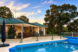 Ein Haus mit Pool, Sitzgelegenheiten im Freien und einer überdachten Terrasse.