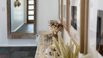 A hallway with a wooden door, a mirror, and a wall with framed pictures.