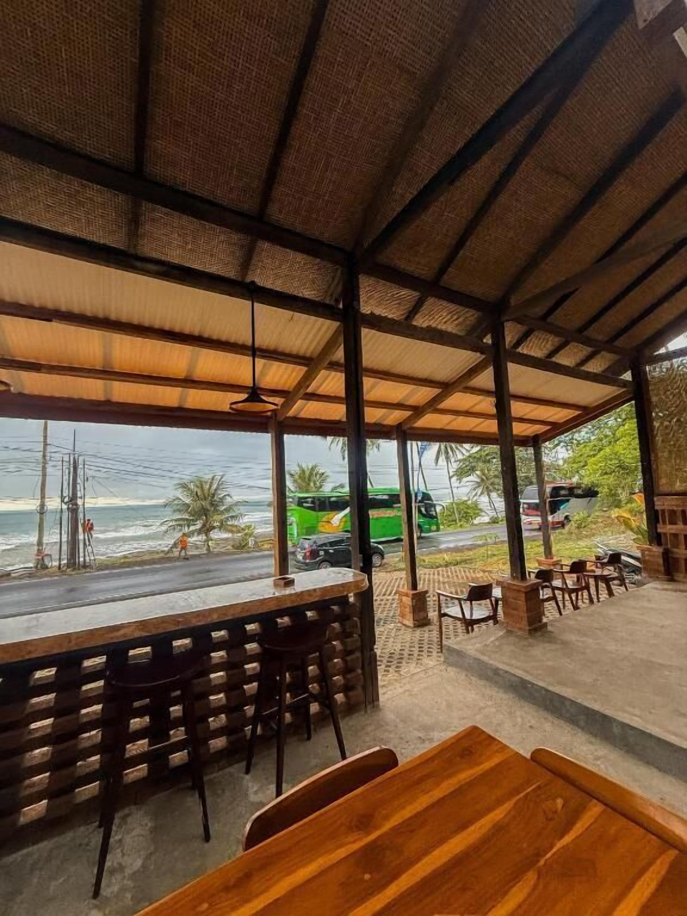 A covered outdoor seating area with a view of the beach and ocean.