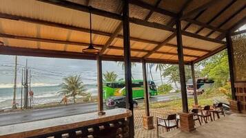 A covered outdoor seating area with a view of the beach and ocean.