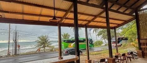 Uma área de estar coberta ao ar livre, com vista para a praia e o oceano.
