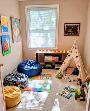 A child's playroom with a tent, bean bags, alphabet mats, and toys.