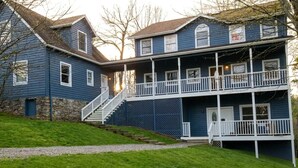 A two-story house with a front porch, stone foundation, and a staircase leading to the entrance. - •LAST MINUTE DISCOUNTS• 6BR Epic Views + BBQ + Fully Stocked Kitchen• (Boone)
