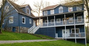 A two-story house with a front porch, stone foundation, and a staircase leading to the entrance.