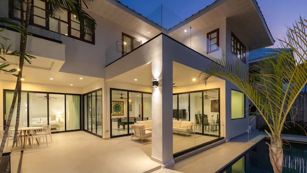 A modern house with a pool, glass doors, and a dining area. - Grand Hill Mansion (Hua Hin)