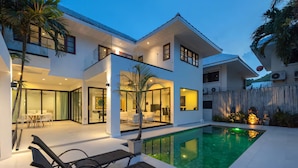 A modern two-story house with a swimming pool, glass doors, and outdoor furniture. - Grand Hill Mansion (Hua Hin)