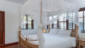 A bed with a canopy, wooden headboard, and bedside table. - Grand Hill Mansion (Hua Hin)