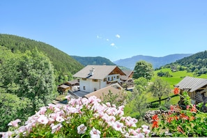 Un pueblo de montaña con casas tradicionales, abundante vegetación y cielo despejado.