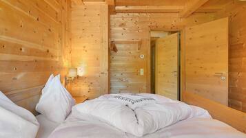 Ein holzgetäfeltes Zimmer im Blockhausstil mit einem Bett, einer Wandleuchte und einer Tür.