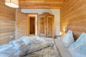 Una habitación con paneles de madera, una cama, un armario y una puerta que da a otra habitación.