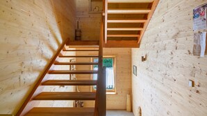 Interior de madera con una escalera, paredes de madera y un ventanal.