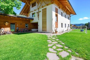 A wooden house with a stone pathway leading to a grassy area and a soccer goal.