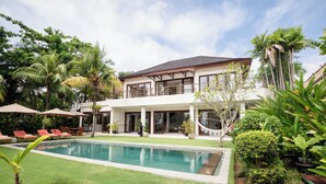 A two-story house with a swimming pool, outdoor seating, and lush greenery. - Dream View Villa - 5 Br (Pecatu)