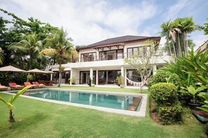 A two-story house with a swimming pool, outdoor seating, and lush greenery. - Dream View Villa - 5 Br (Pecatu)