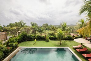 A swimming pool with a view of a lush garden and distant buildings. - Dream View Villa - 5 Br (Pecatu)