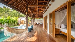 A wooden deck with a hammock, a pool, and a bed with a canopy. - Villa Calypso - 3 Br (Seminyak)