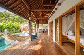 Eine Holzterrasse mit Hängematte, Pool und einem Bett mit Baldachin.