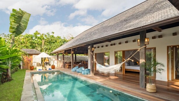 A poolside area with a wooden deck, a hammock, and a covered seating area. - Villa Calypso - 3 Br (Seminyak)