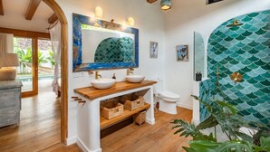 A bathroom with a wooden vanity, two sinks, a large mirror, and a decorative wall. - Villa Calypso - 3 Br (Seminyak)