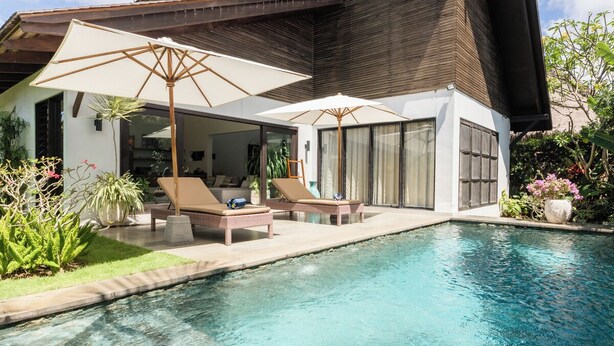 Ein modernes Haus mit Swimmingpool, Liegestühlen und Sonnenschirmen.