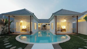 A poolside area with two connected rooms, a pool, and a wooden deck. - Bingin Beach Villas (Pecatu)