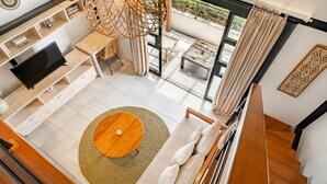 Un salon moderne doté d’un téléviseur à écran plat, d’une table basse ronde, d’un canapé et d’un coin repas avec une table et des chaises.