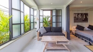 Un vaste espace de vie comprenant un canapé, une table basse et un lit avec une literie à rayures.
