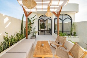 Eine Terrasse im Freien mit einem Holztisch, Korbstühlen und einer Couch.