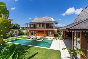 Ein zweistöckiges Haus mit Swimmingpool, Balkon und Garten.