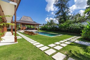 Ein Garten mit Swimmingpool, überdachter Sitzgelegenheit und gepflegtem Rasen.