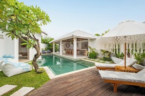 Ein Poolbereich mit Liegestühlen, einer überdachten Sitzgelegenheit und einer Holzterrasse.
